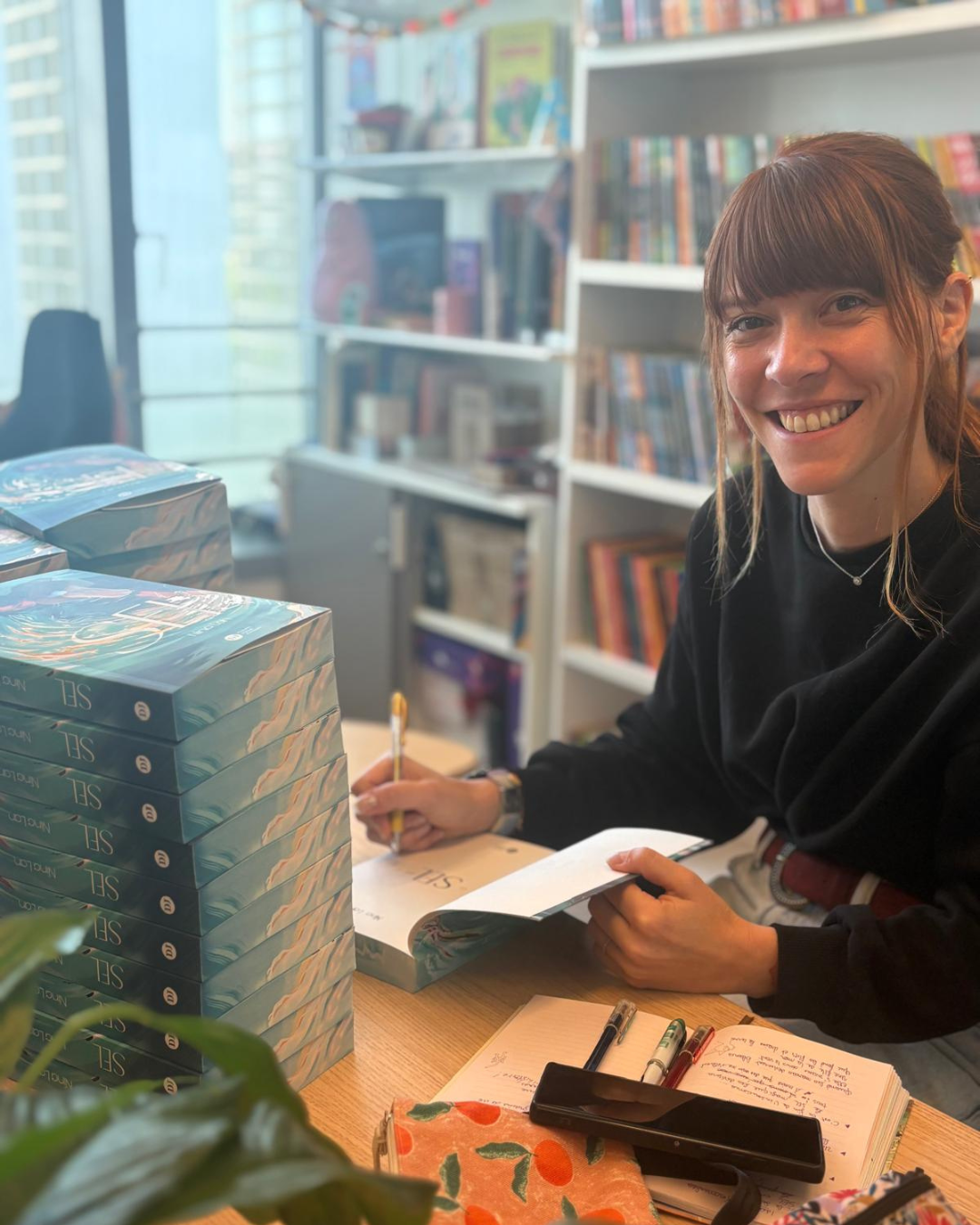 visuel de l'autrice en train de dédicacer les ouvrages